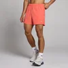 Een man draagt een korte, koraalkleurige sportbroek met een elastische tailleband en een klein logo.