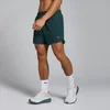 Een man draagt een donkergroene MP Tempo short met witte sokken en sportschoenen.