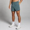 Een man draagt donkerleigrijze sportshorts met een elastische tailleband en witte sokken met sportschoenen.