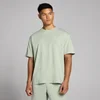 Een man draagt een pastelgroen, oversized T-shirt met korte mouwen en een klein logo.
