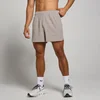 Een man draagt een korte, bruine trainingsshort met elastische tailleband en witte sokken met sportschoenen.