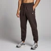 Een man draagt een chocoladebruine joggingbroek met trekkoord en een klein wit logo.