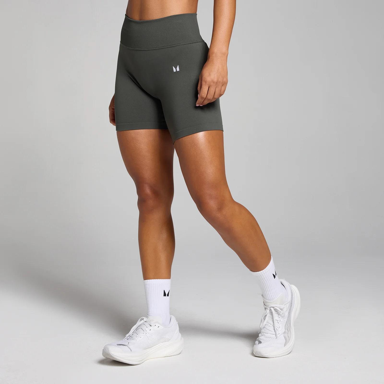 Een nachtgrijze, middelhoge, naadloze short van MP, gedragen met witte sokken en sportschoenen.