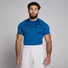 Een man draagt een blauw, strak trainingsshirt met korte mouwen en een wit logo.