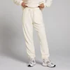 Een persoon draagt een lichtroomwitte fleece joggingbroek met trekkoord en elastische enkels.