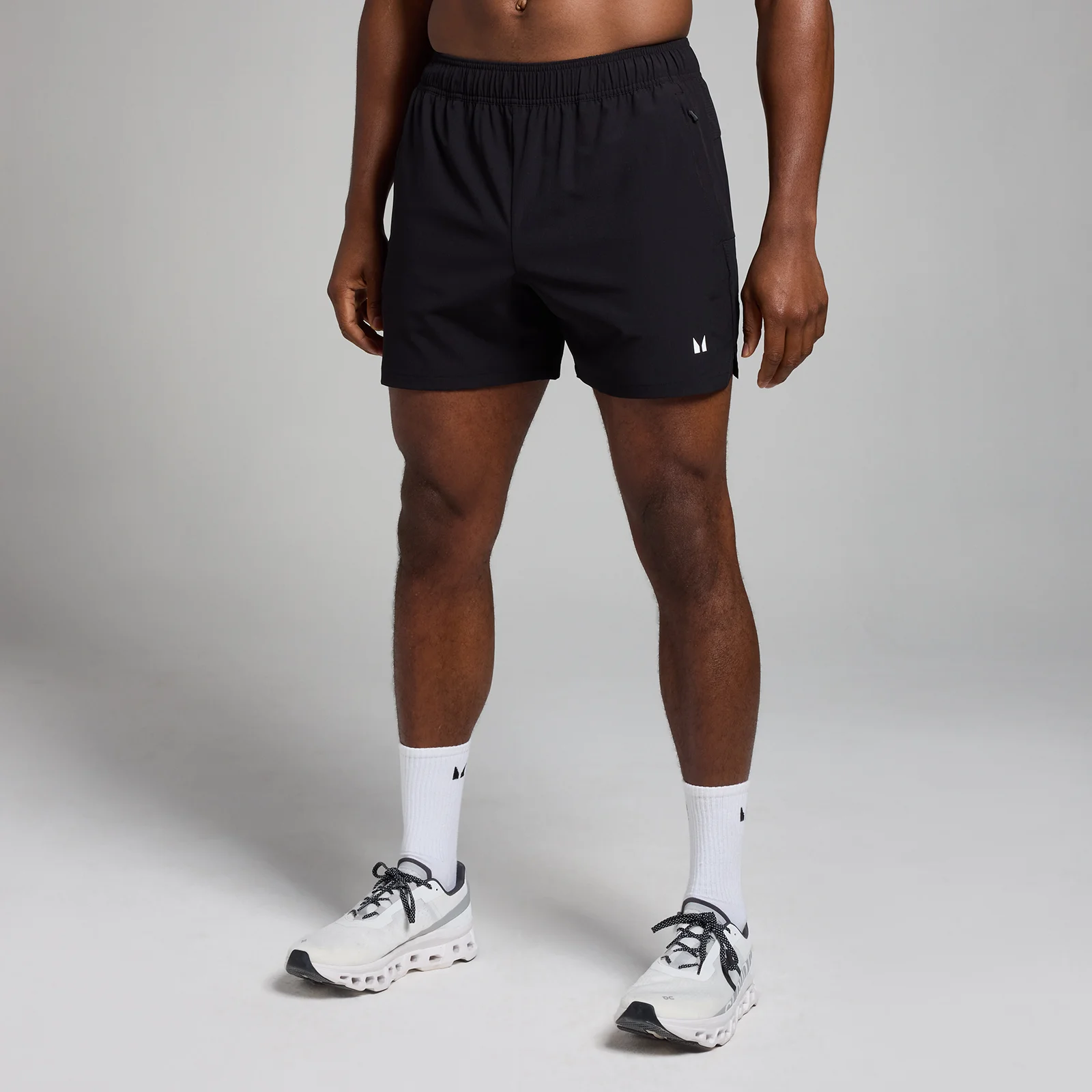 Een man draagt een zwarte trainingsshort met een elastische tailleband en een klein logo.