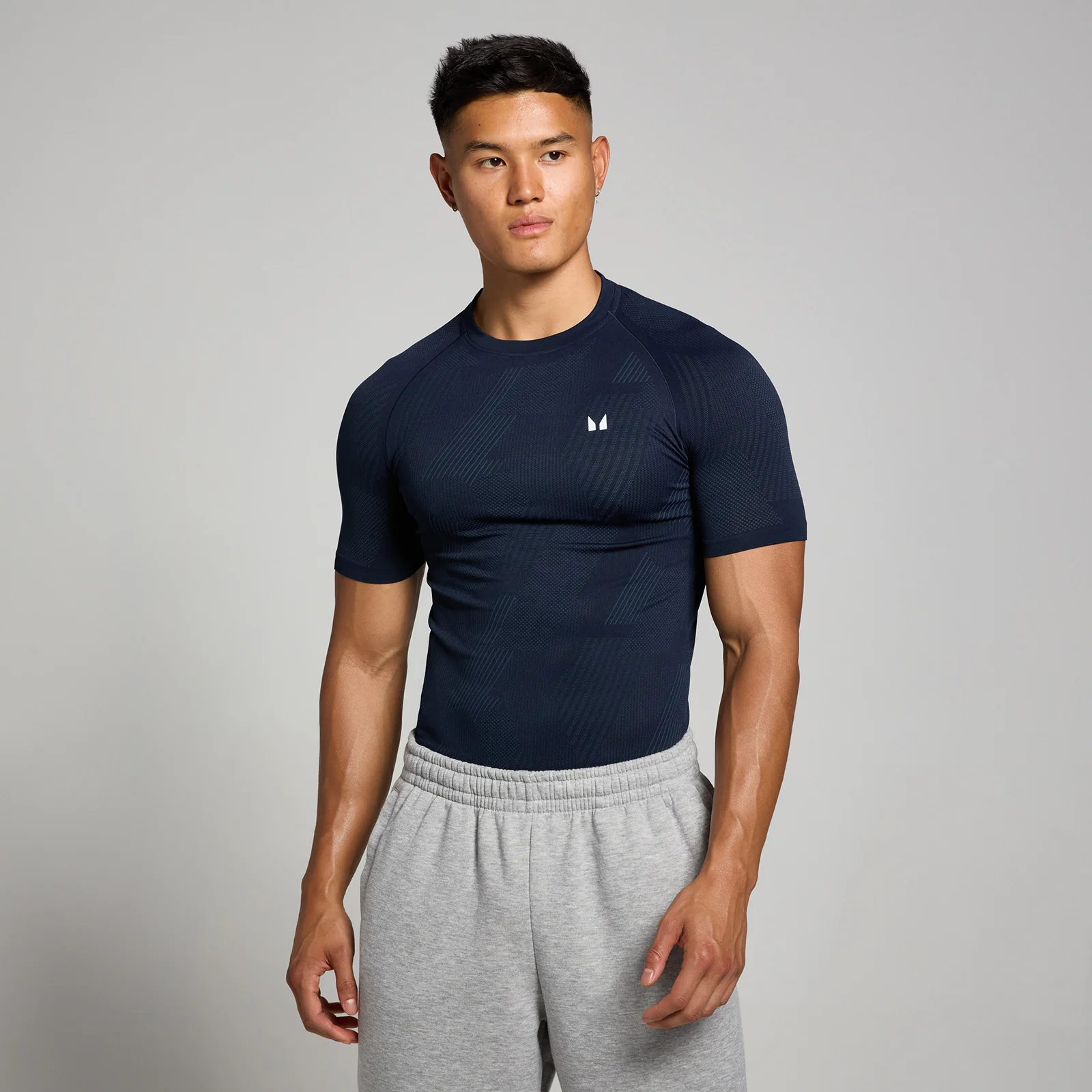 Een marineblauw, nauwsluitend T-shirt met korte mouwen en een klein wit logo op de borst.