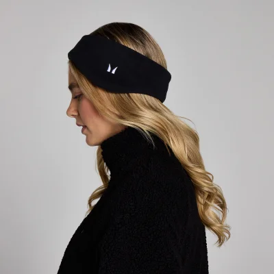 Een vrouw draagt een zwarte fleece haarband met een wit logo.