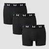 Drie zwarte boxershorts met een witte band met logo, gestapeld op een grijze achtergrond.