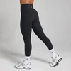 Een vrouw draagt een zwarte, hoge taille legging met witte sokken en sportschoenen.