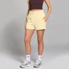 Een vrouw draagt een citroengele sweatshort met trekkoord en zakken.