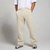 Een man draagt een haverwitte, oversized joggingbroek met zakken en een elastische tailleband.