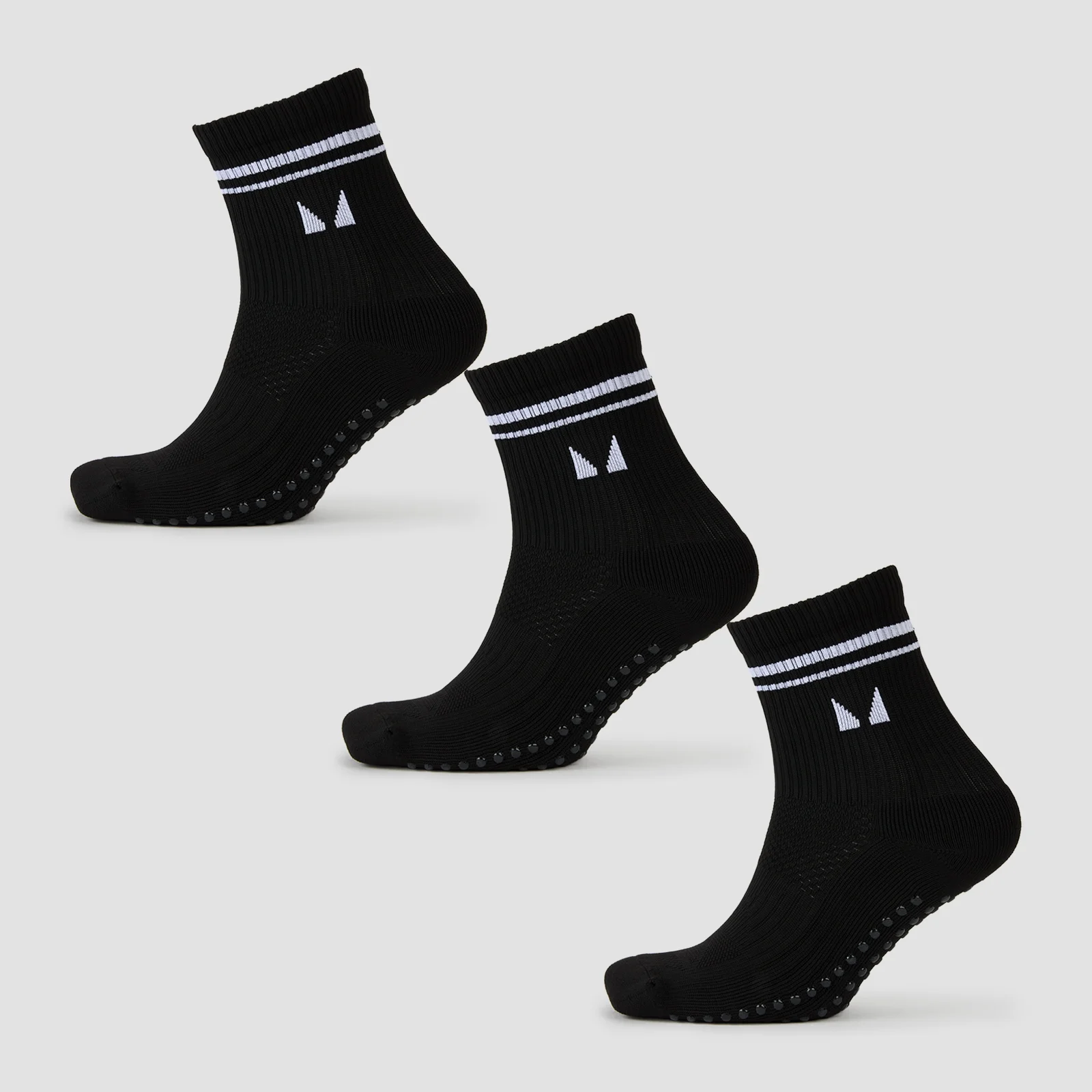 Drie zwarte sokken met witte strepen en een logo, voorzien van antislip nopjes aan de onderkant.