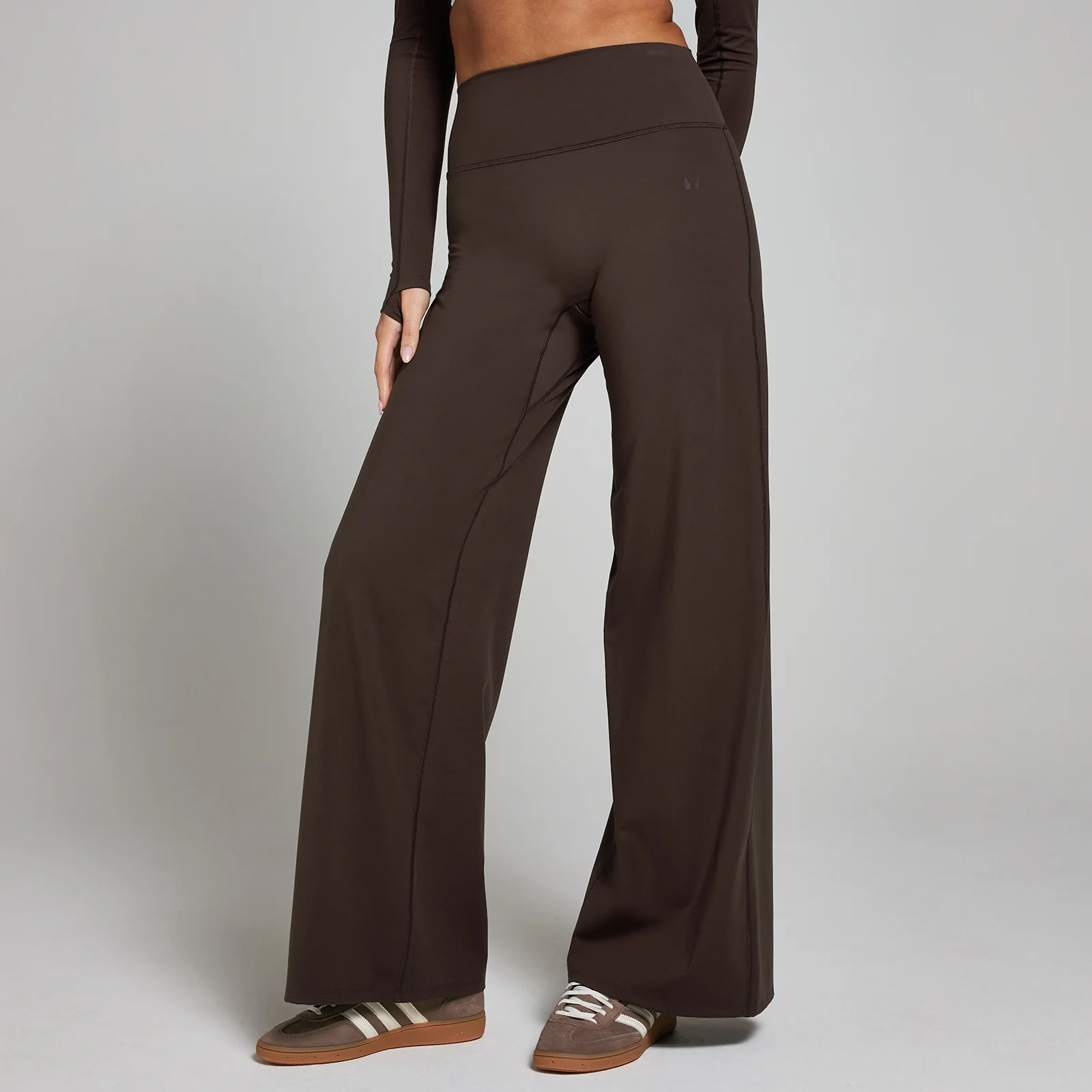 Een cacaobruine legging met wijde pijpen, gedragen door een model met bijpassende top en bruine sneakers.