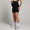 Een zwangere vrouw draagt een zwarte, korte sportbroek met hoge taille en witte sportschoenen.