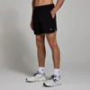 Een man draagt een zwarte, geweven sportshort met een klein, wit logo op de pijp.