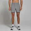 Een man draagt een grijze, geweven sportshort met een elastische tailleband en zakken.