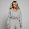 Een vrouw draagt een gemêleerd grijze hoodie met rits en bijpassende joggingbroek.
