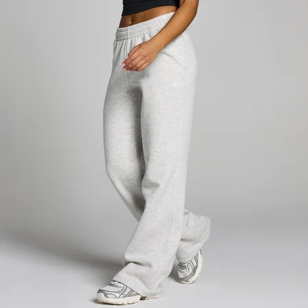 Een vrouw draagt een gemêleerde grijze joggingbroek met rechte pijpen en een elastische tailleband.