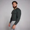 Een man draagt een geribbeld, zwart shirt met lange mouwen en grijze joggingbroek.
