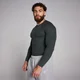 Een man draagt een geribbeld, zwart shirt met lange mouwen en grijze joggingbroek.